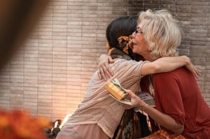 older woman hugging dauther outdoors thanking for gift
